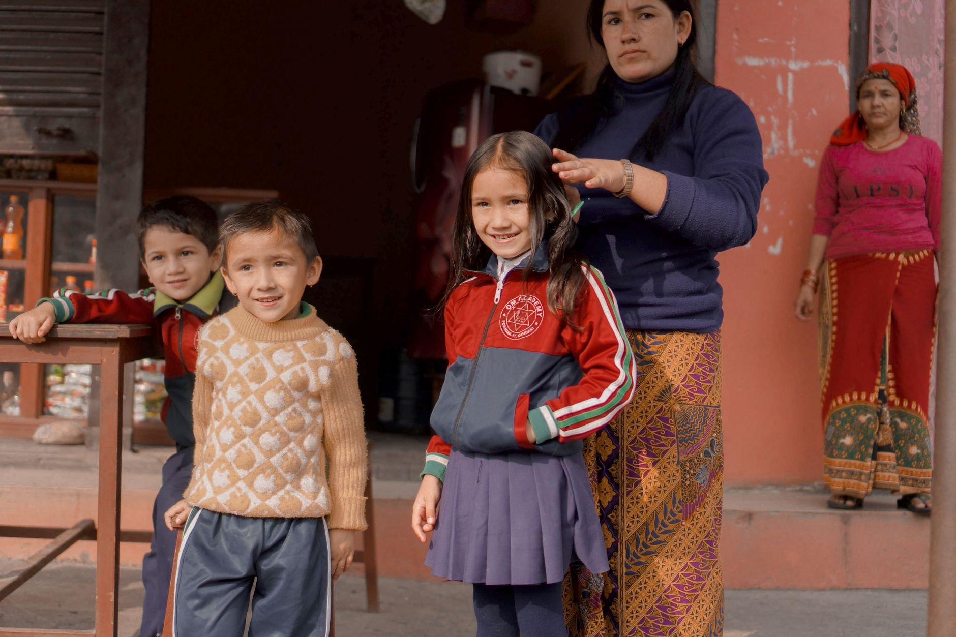 A joyful family moment on a vibrant Nepalese street, showcasing children in school uniforms.